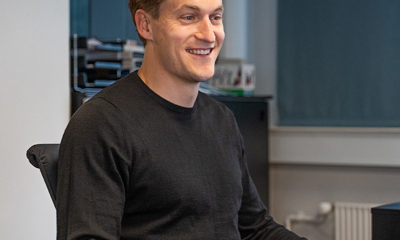 Portræt af Rasmus Bahr Lund, ESG Manager hos C.W. Obel Ejendomme, siddende ved en computer