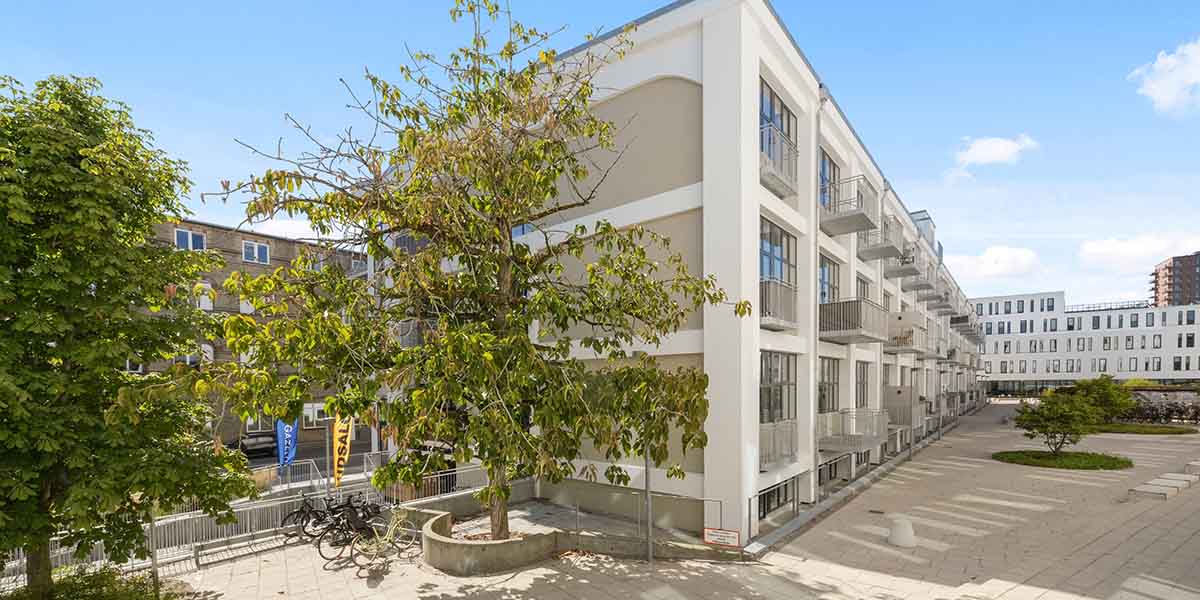 ObelHus facade med stort grønt træ ved siden og blå himmel